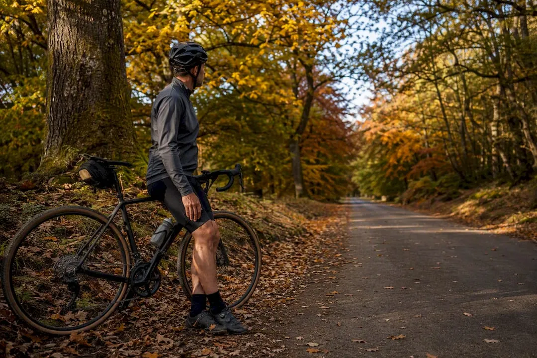Cyclist stopping among autumn arboretum trees