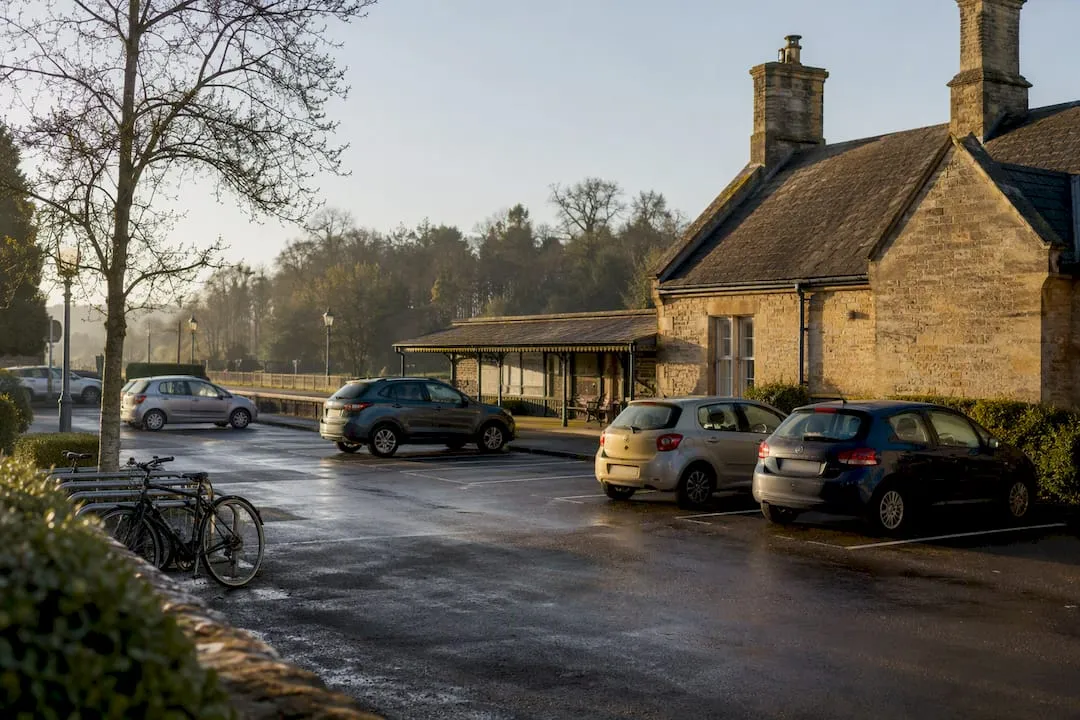 Cars and bicycle racks in the car park of a honey-stone station building on a frosty morning