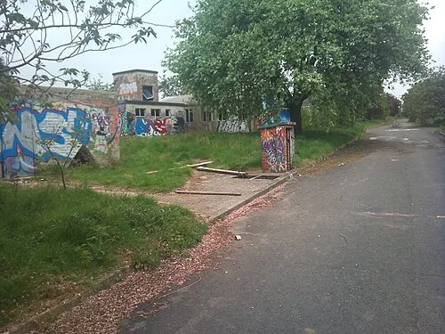 A Photo of the HMS Royal Arthur (shore establishment), showing graffitied buildings and the road which runs up up the centre