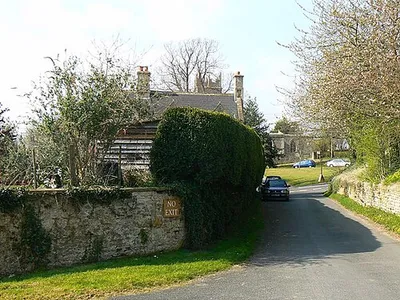 A view towards the centre of Coleshill, Oxfordshire The top of the tower of St Faith with All Saints church is visible above the roof of the house.
