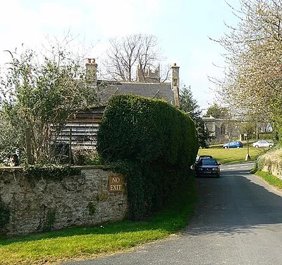 A view towards the centre of Coleshill, Oxfordshire The top of the tower of St Faith with All Saints church is visible above the roof of the house.