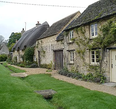 Cottages at Minster Lovell, Oxfordshire. The view westwards with 1006336 in the distance.
On the right is Lovell Cottage which has part of an old tombstone over the front door.

The channel-drain in front of the cottages was dug for excess water to reach the river.