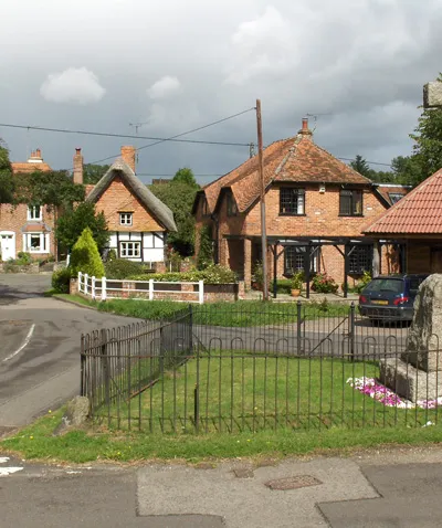 East Garston, Berkshire. At the junction of Front Street, Back Street and Roger's Lane. In the foreground is the parish war memorial. The white railings are on the bridge over the River Lambourn and are beside the old forge.