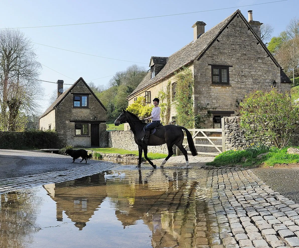A rider and her dog cross the River Dunt through the ford at Duntisbourne Leer. Duntisbourne Leer is a Cotswolds village located in Gloucestershire approximately 5 miles northwest of Cirencester. .mw-parser-output .messagebox{margin:4px 0;width:auto;border-collapse:collapse;border:2px solid var(--border-color-progressive,#6485d1);background-color:var(--background-color-neutral-subtle,#fbfcff);color:var(--color-base,#202122);box-sizing:border-box;border-inline-start-width:8px}.mw-parser-output .messagebox.mbox-small{font-size:88%;line-height:1.25em}.mw-parser-output .mbox-warning,.mw-parser-output .mbox-speedy{border:2px solid var(--border-color-error,#b22222);background:var(--background-color-error-subtle,#ffdbdb);border-inline-start-width:8px}.mw-parser-output .mbox-serious,.mw-parser-output .mbox-delete,.mw-parser-output .mbox-stop{border:2px solid var(--border-color-error,#b22222);border-inline-start-width:8px}.mw-parser-output .mbox-issue,.mw-parser-output .mbox-content{border:2px solid #f28500;background:var(--background-color-warning-subtle,#ffe);border-inline-start-width:8px}.mw-parser-output .mbox-query,.mw-parser-output .mbox-style{border:2px solid #f4c430;background:var(--background-color-warning-subtle,#ffe);border-inline-start-width:8px}.mw-parser-output .mbox-shit{border:2px solid #960;border-inline-start-width:8px}.mw-parser-output .mbox-license{border:2px solid #88a;border-inline-start-width:initial}.mw-parser-output .mbox-legal{border:2px solid var(--border-color-notice,#666);background:var(--background-color-base,#fff);border-inline-start-width:8px}.mw-parser-output .mbox-honor{border:2px solid #ca3;background:var(--background-color-warning-subtle,#fcf4db);border-inline-start-width:8px}.mw-parser-output .mbox-growth{border:2px solid #8d4;background:var(--background-color-success-subtle,#d5fdf4);border-inline-start-width:8px}.mw-parser-output .mbox-move{border:2px solid #93c;border-inline-start-width:8px}.mw-parser-output .mbox-protection,.mw-parser-output .mbox-message{border:2px solid var(--border-color-base,#aaa);border-inline-start-width:8px}.mw-parser-output .messagebox .mbox-text{border:none;padding:0.25em 0.9em;width:100%}.mw-parser-output .messagebox .mbox-image{border:none;padding:2px 0 2px 0.9em;text-align:center}.mw-parser-output .messagebox .mbox-imageright{border:none;padding:2px 0.9em 2px 0;text-align:center}.mw-parser-output .messagebox .mbox-empty-cell{border:none;padding:0;width:1px}.mw-parser-output .messagebox .mbox-invalid-type{text-align:center}@media(min-width:720px){.mw-parser-output .messagebox{margin:4px 10%}.mw-parser-output .messagebox.mbox-small{clear:right;float:right;margin:4px 0 4px 1em;width:238px}}body.skin--responsive .mw-parser-output table.messagebox img{max-width:none!important}Wikidata has entry Leigh  Cottage (Q26380861) with data related to this item.Wikidata has entry Turner's (Q26592314) with data related to this item.