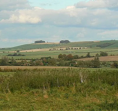 Another view north-east from Windmill Hill, near Winterbourne Monkton A slightly closer view to the north-east and Hackpen Hill is clearly visible in square SU1274. The white horse is discernible as the white speck beneath the clump of trees on the centre horizon. The village of Winterbourne Monkton nestles among the trees in the centre of the image.