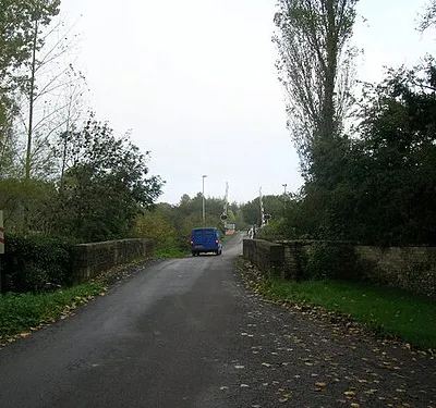 Bridge and crossing at Bruern Abbey Stone bridge over the River Evenlode with railway level crossing beyond. Photo taken at one entrance to Bruern Abbey, which is now a Prep school but clearly has an interesting history with the exact location of the real Abbey (founded in 1147) still a mystery.