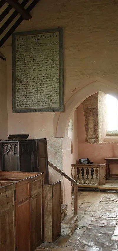 The interior of St Oswald's church in Widford, Oxfordshire.  A rustic interior with box pews ochre walls and medieval wallpaintings.