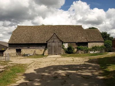 Barn, Upton St. Leonards This magnificent barn is at Manor Farm, on Portway. The following description is taken from the description on http://www.stroud.gov.uk/info/listed_buildings/upton_stleonards.pdf :
"Large barn with attached stable at east end. C15, possibly
earlier; late C17 stable. Very large coursed and squared
limestone; timber framing; coursed rubble to stable; stone slate
roof (clay pantile to north slope). Off-centre south porch to 6-
bay barn; stable with loft. South side: stone base walls with
chamfered plinth and buttresses; gabled porch with plank barn doors
and outshut to right; weatherboarded porch gable and upper part of
barn walls; low opening in wall to left of porch with plank doors;
plain stone side wall to stable. East end: barn end is half-hipped
with small gablet, gabled stable with 2 stable doors having timber
lintels; central loft door over with timber lintels; 3 rows of
a pigeon holes in gable apex. North side: weatherboarded above
buttressed stone base walls as to south; central porch with raised
sprocketted roof; attached shelter sheds are not of special
interest. West end: weatherboarded half-hipped gable end with
I 3 gablet above buttressed stone base wall.
S= Interior has 7 raised cruck trusses with very high cambered collars
and arched bracing; 2 rows of purlins and ogee-curved wind bracing:
close studded end walls; small framing along sides. Internal span Il of approximately 8.2m across feet of crucks. Rafters and framing
are original: C15 work is largely intact with little evidence of
repair or replacement. C19 iron tie-rods sag and appear
unnecessary. A lofty and elegant structure. Important barn and

one of the best in the county. Possibly built as Tithe Barn for Gloucester Abbey. (N.W. Alcock, Cruck Construction: An Introduction and Catalogue, Q 1981).