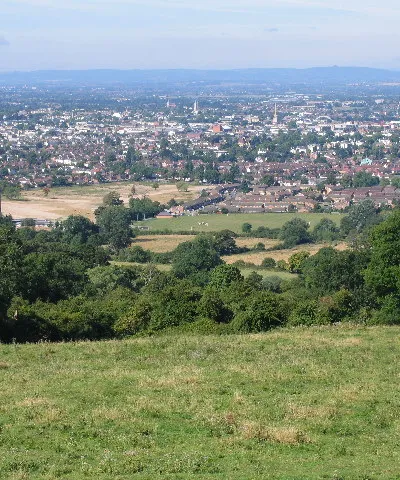 Above Noverton. This square is filled by the steep south western slopes of the southern end of the Cleeve Hill/Common area. This view looks south west down the slopes across Cheltenham and into the Severn Vale. The green building in the left foreground is part of the old GCHQ complex.