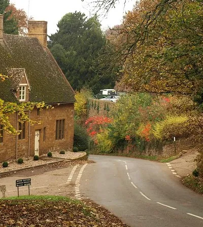 Alkerton, Oxfordshire: road from Alkerton Barn into the village past Well Lane (left) and an ironstone house