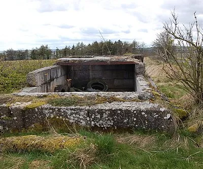 Crumbling pillbox near Charlton Abbots View looks westwards from this spot high up on the Cotswold plateau. This re-inforced concrete structure standing at the top of a steep hill is like a WW2 type 23 pillbox in plan although no embrasures are immediately evident. The site enjoys excellent views in all directions over the Cotswolds and as far as the Malverns to the north-west. One can only speculate as to its original purpose but it seems likely it acted as an observation platform possibly with a light anti-aircraft machine gun in the open half of the structure. Records indicate that the nearest WW2 airfield was at Northleach some 7 miles distant.