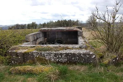 Crumbling pillbox near Charlton Abbots View looks westwards from this spot high up on the Cotswold plateau. This re-inforced concrete structure standing at the top of a steep hill is like a WW2 type 23 pillbox in plan although no embrasures are immediately evident. The site enjoys excellent views in all directions over the Cotswolds and as far as the Malverns to the north-west. One can only speculate as to its original purpose but it seems likely it acted as an observation platform possibly with a light anti-aircraft machine gun in the open half of the structure. Records indicate that the nearest WW2 airfield was at Northleach some 7 miles distant.