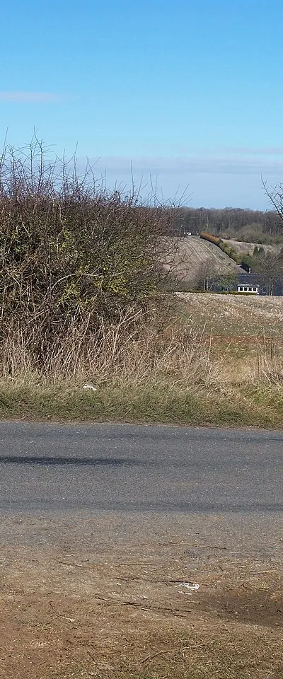 Crossing of a bridleway and a minor road near Lidstone, Oxfordshire. The roof visible through the gap in the hedge is that of Lidstone Court.