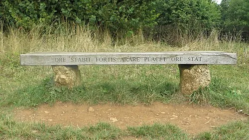 This is a bench at the Whispering Knights, Rollright Stones, in Oxfordshire UK. It bears a Dog Latin inscription.