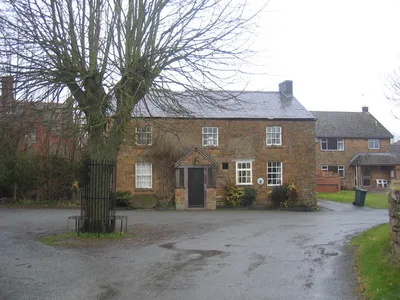 The former Sunrising Inn, Church Lane, Claydon, Oxfordshire, seen from the south. It closed in 1990 and is now a private house. The white and blue circular glazed plaque between the windows on the ground floor shows it was once a tied house of the Hunt Edmunds brewery of Banbury.