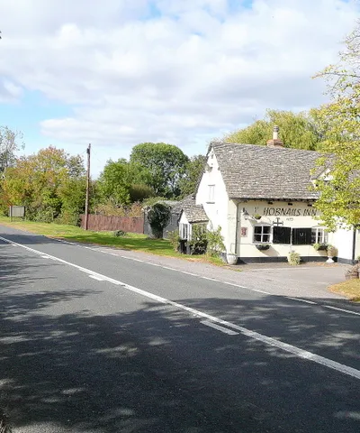 B4077 at the Hobnails Inn Looking west towards Tewkesbury.
The porch at the end of the building sags!