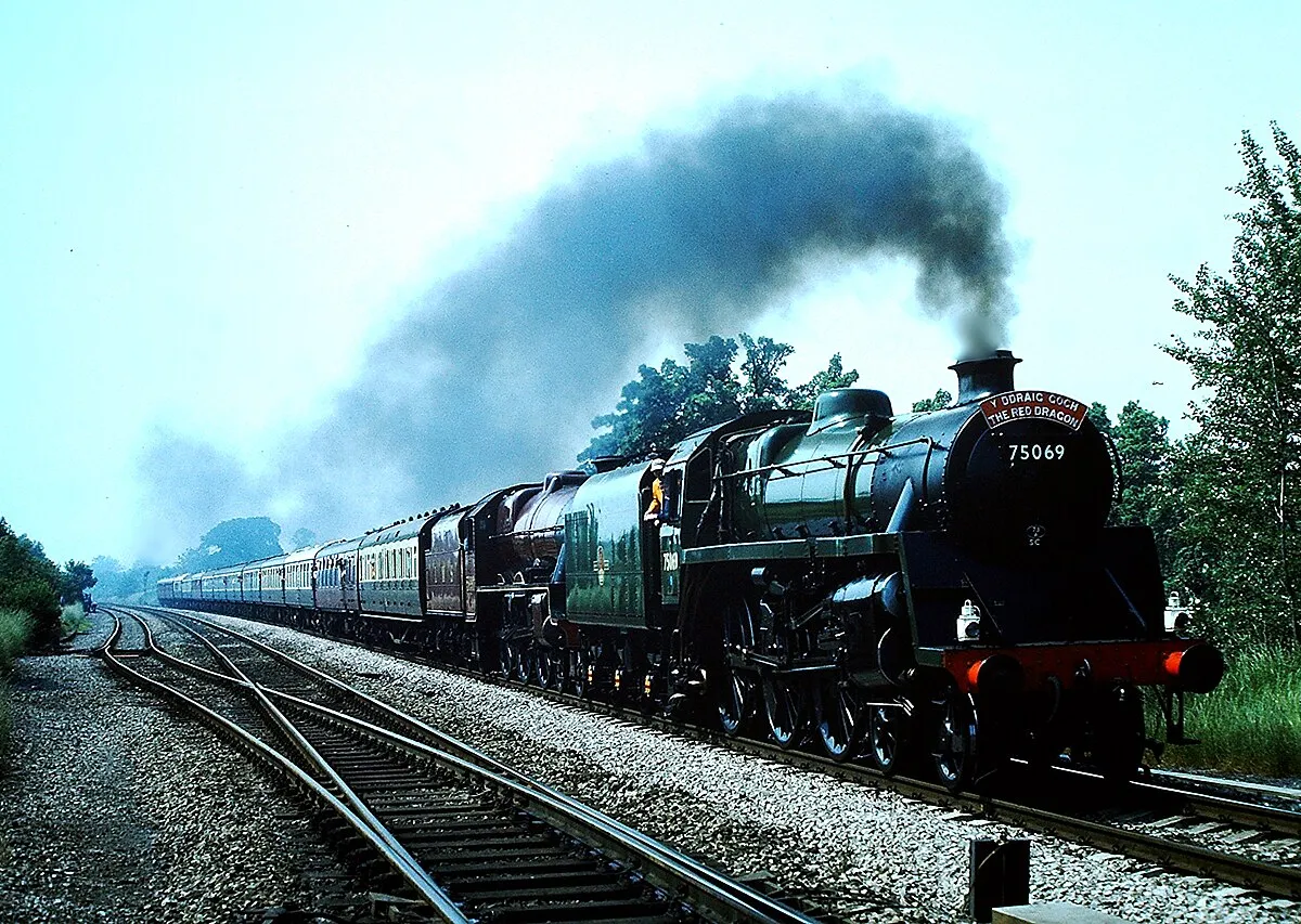 BR Riddles Standard Class "4MT" 4-6-0 No.75069 with double chimney and BR1B tender in BR lined green livery and LMS Stanier Class "6P" or "Jubilee" Class 4-6-0 No.5690 (later BR No.45690) "Leander" in LMS Crimson Lake livery at full speed near Gloucester on the Swindon - Hereford "Red Dragon", 07/86. Scanned photograph taken with Canon AE-1 Program.