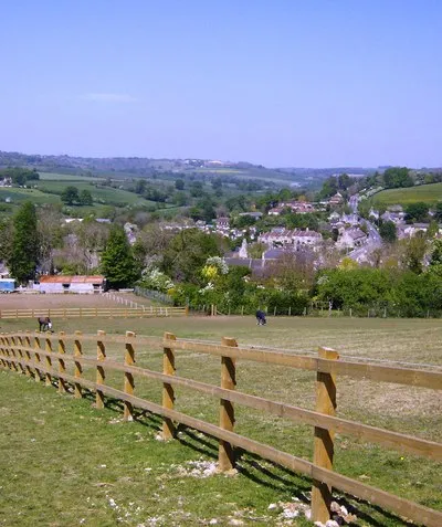 Box boxed The features of most of the grid square containing Box can be seen here, looking north from a footpath that descends to the village.  The A4 can be seen ascending Box Hill in the centre right of the photo.  The railway line comes out of a small tunnel just behind the line of trees in the left middle distance (Middle Hill).  It runs left to right on an embankment behind the village (above the white roofed building) then goes underneath the A4 and almost immediately enters Box tunnel.  The valley in the centre background is that of the By Brook, having flowed towards us from Castle Combe.  It flows under the railway, in front of Middle Hill and off to the west (left) towards Bath.